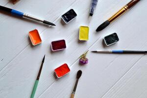 Tools for painting on the white wooden desk. Brushes and paints on the table. Painter's workplace. photo