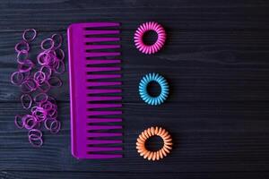 Colorful and bright cosmetics. Beauty care tools. Beauty salon. Girl's paradise. Nail polishes, sequins, pink hair bands and comb on a dark blue wooden desk. Bright still life of beauty instruments. photo