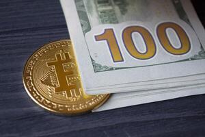 Golden bitcoin and dollars in male hand on a dark blue wooden background. Gold coin of cryptocurrency. photo