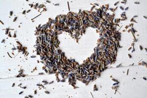 Heart symbol from the lavender flowers on the white wooden table. Lavender flavor. photo