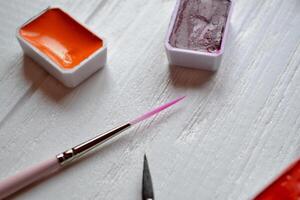 Tools for painting on the white wooden desk. Brushes and paints on the table. Painter's workplace. photo