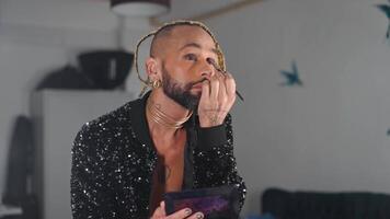 une homme avec une barbe et une or cheveux pièce appliquant faire en haut dans de face de le miroir video