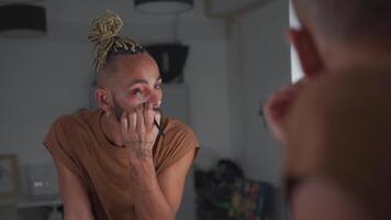 une homme avec une barbe et une or cheveux pièce appliquant faire en haut dans de face de le miroir video