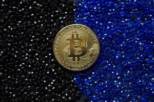 Golden bitcoin on a black and blue rhinestones. photo