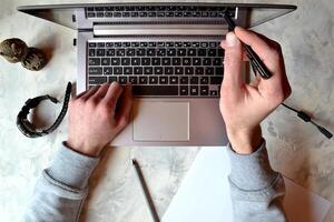 Bussinesman working at office. Laptop, pencil, stylus, watch, paper and male hands. photo