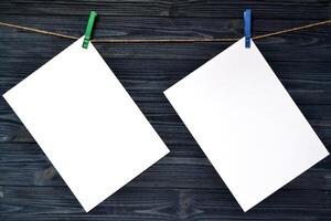 blanco sábana de papel pegado con un pinza de ropa en un de madera pared. foto