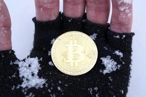 dorado bitcoin en masculino mano. oro moneda de criptomoneda foto