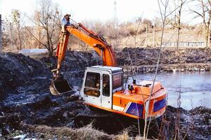 Excavation in the park. Excavator working on the lake. photo