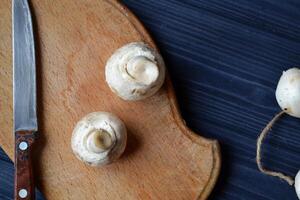 Mushrooms on the dark blue wooden desk. Cooking champignons. photo