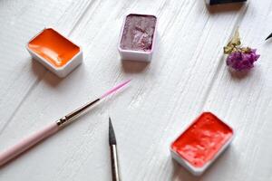 Tools for painting on the white wooden desk. Brushes and paints on the table. Painter's workplace. photo