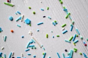 Colorful sugar on the table. Bright sweet powder for cake on the white wooden background. Beautiful abstract background. photo