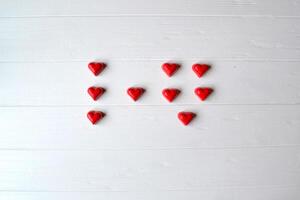 Red candies on the white wooden table. Background for greeting card on Valentine's day with place for text. photo