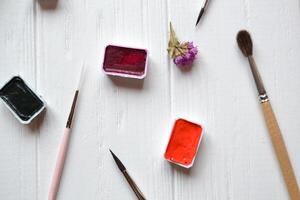 Tools for painting on the white wooden desk. Brushes and paints on the table. Painter's workplace. photo