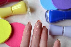 Creative beauty background. Nail polishes, glitter and sponges in trendy colors. photo