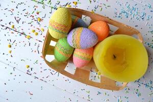 Colorful easter eggs with flowers and yellow candle in the basket. Beautiful easter background. Easter card. Homemade holiday decor. photo