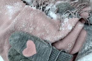 Winter woolen textile. Scarf and mittens on the snow. Beautiful winter background. Cold season. photo