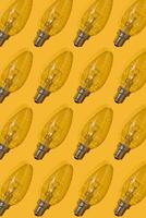 Yellow background. Electric light bulbs pattern. An old glass electric light bulb with a tungsten filament. The concept of electricity consumption and saving. photo