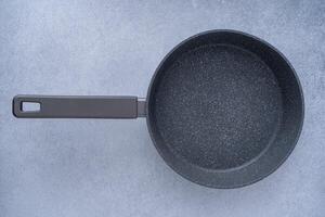 New granite frying pan on a gray background, top view. Empty fry pan with handle. photo