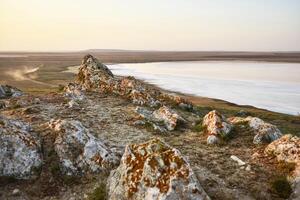 evening landscape shot from the rocks above a salt lake on the field you can see dust from a passing car photo