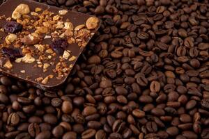 A bar of craft chocolate with various nuts, berries and dried fruits. Coffee beans. Food background. photo