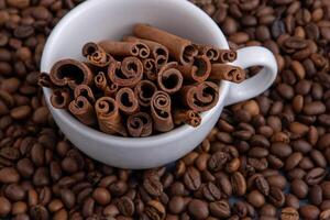 Coffee beans and cinnamon sticks in a cup. Food drink background. photo
