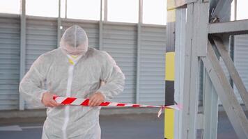 a man in a protective suit holding a red ribbon video