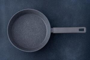New granite frying pan on a gray background, top view. Empty fry pan with handle. photo
