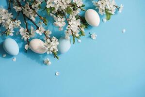 Blue and white eggs amidst cherry blossoms on blue background evoking Easter and spring photo