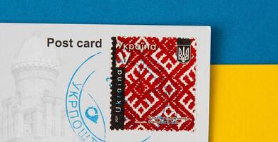 Ukrainian postage stamp with Vyshyvanka - a fragment of a national dress shirt. Red embroidery. Ukrposhta postmark on a postcard. Ukraine, Kyiv - February 24, 2023. photo