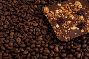 A bar of craft chocolate with various nuts, berries and dried fruits. Coffee beans. Food background. photo