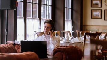 Portrait of goodlooking man sitting at table in restaraunt with laptop computer photo