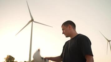 ein Mann im ein schwer Hut Stehen im Vorderseite von ein Wind Turbine draussen video