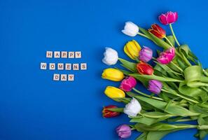 contento De las mujeres día tarjeta. de madera letras. mezcla de primavera tulipanes flores antecedentes con flores tulipanes de cerca diferente colores. multicolor primavera flor. regalo. rojo, rosa, blanco y amarillo. foto