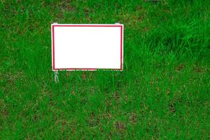 Pointer sign on the lawn with green grass. Banner layout with place for the text dog walking is prohibited, do not walk on the lawn, it is dangerous. Information board layout. Mockup. photo