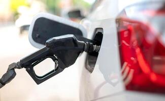 el boquilla combustible llenar petróleo dentro coche tanque a bomba gas estación foto