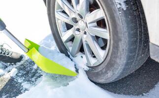 un hombre es palear nieve cerca ruedas para preparar el la carretera para conveniencia. foto