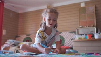 un pequeño niña sentado en un cama escritura en un pedazo de papel video