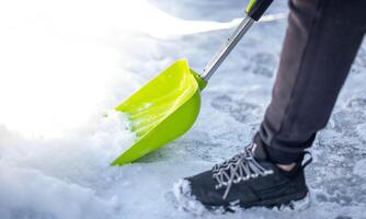 A man is shoveling snow near wheels for prepare the road for convenience. photo