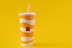 Yellow glass of McDonald's. Paper cup with lid. Takeaway drink. McDonald's logo. Ukrainian, Kyiv - March 02, 2023. photo