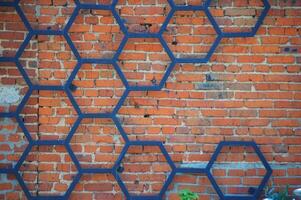 Iron forged decorative pattern of black metal in the shape of a honeycomb on the background of a red brick wall. photo