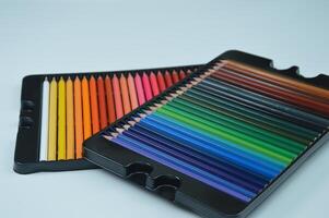 Two boxes with sets of bright colored pencils on a white background. Stationery, materials for creativity, hobby, drawing. photo