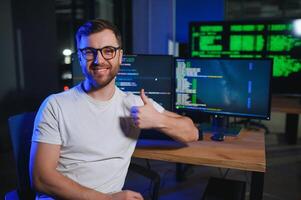 Male programmer working on desktop computer at white desk in office photo