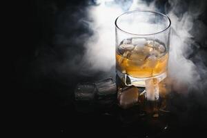 whiskey with ice on black background with smoke photo