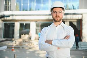 Engineer next to building cranes. Concept - large construction project. Architect directs the construction process. Drawings and tablet in the hands. photo