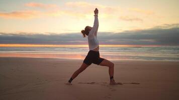 een vrouw aan het doen yoga Aan de strand Bij zonsondergang video