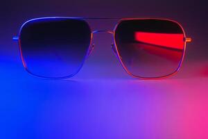 Stylish sunglasses shot using pink and blue abstract colored lighting with copy space. photo