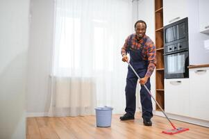 Young african man washes the floor with a mop in the room photo
