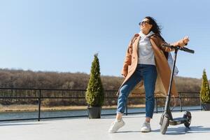 joven hermosa mujer montando un eléctrico scooter a trabajar, moderno chica, nuevo generación, eléctrico transporte, ecología, ecológico transporte, atardecer, eléctrico patineta. foto