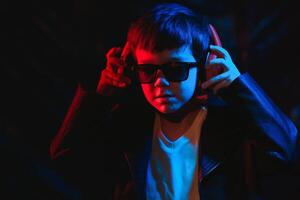 teen boy listening to music with headphones, neon light trending portrait. Looks at the camera photo