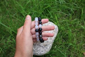 Bracelets made of minerals black agate and white chalcedony in woman's hand. photo